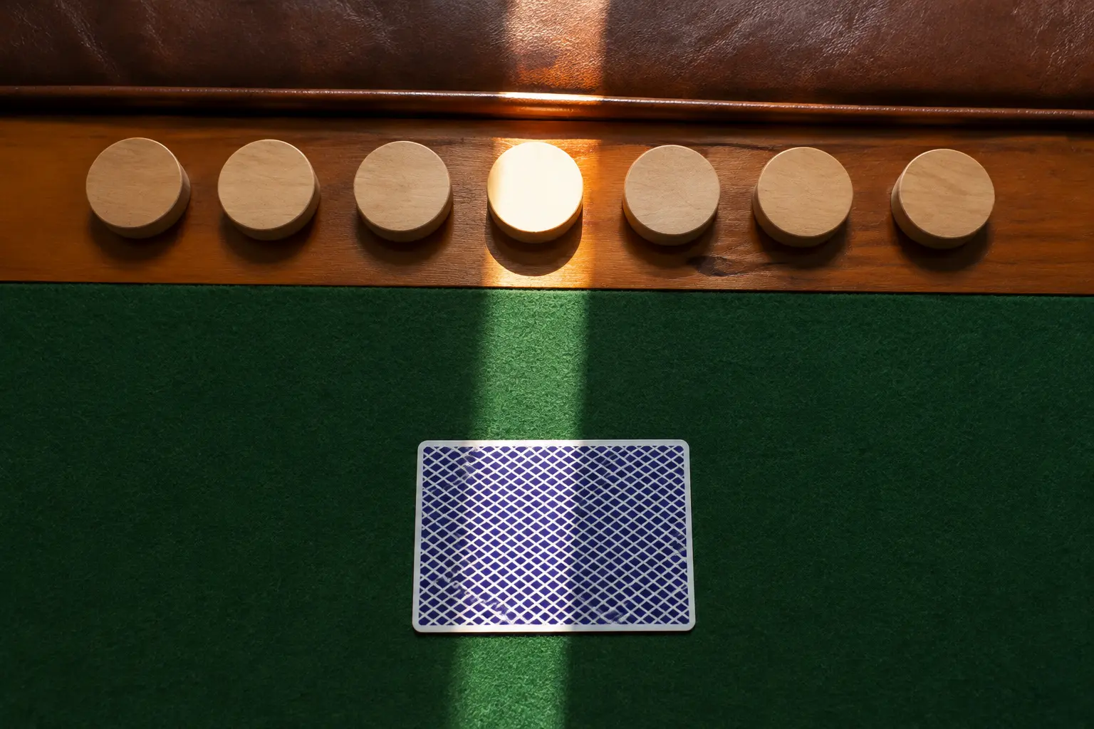 Seven blank wooden day markers beside a face-down unbranded playing card